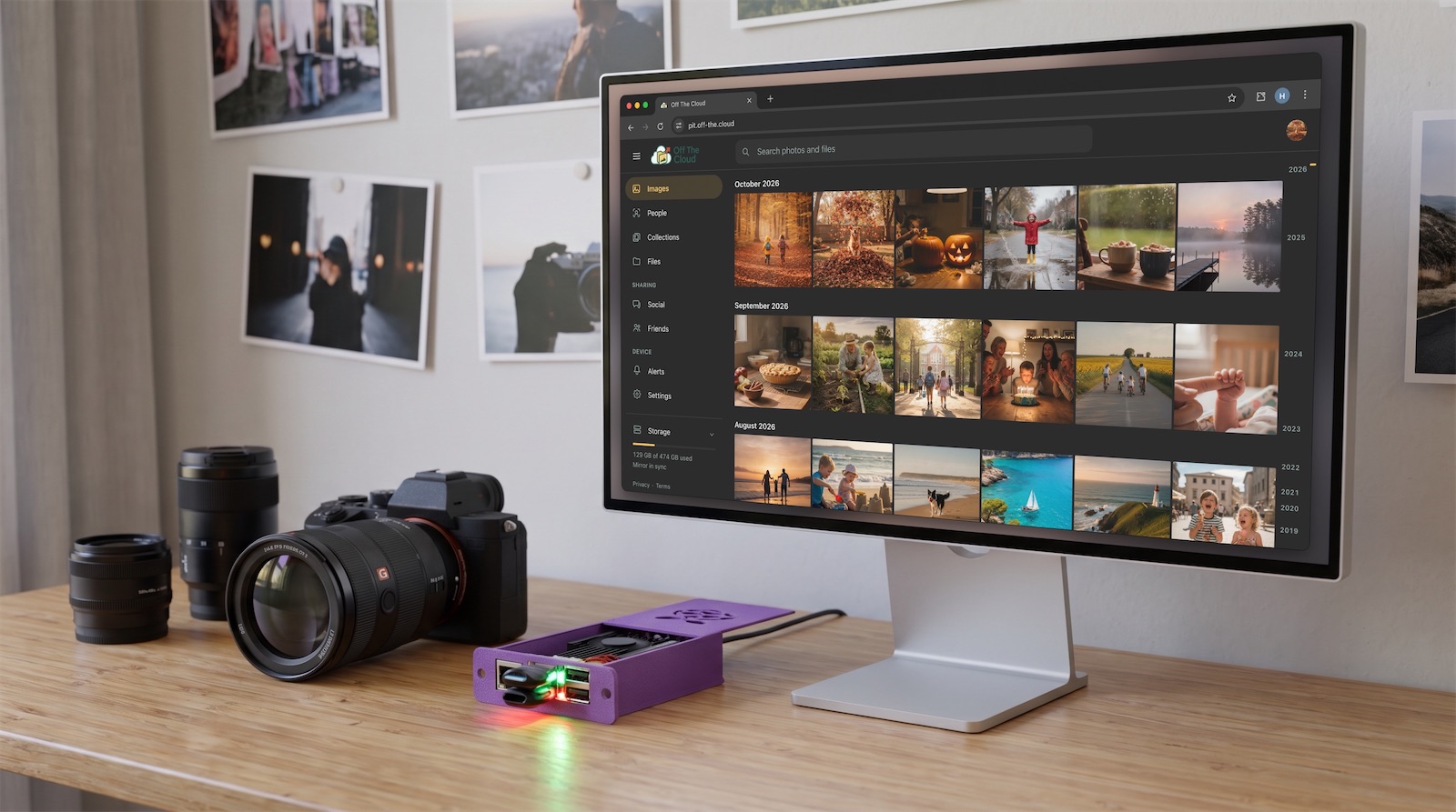 An Off The Cloud device on a desk, next to a camera and a computer showing your photo library
